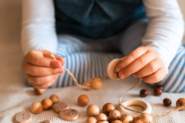 Childs hands threading beads and making bracelet. Childs hands threading beads and making bracelet. Close up. baby bracelet stock pictures, royalty-free photos & images