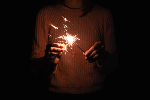 a menina ajusta o fogo ao fundo sparkler, escuro - sparkler sparks new years eve human hand - fotografias e filmes do acervo