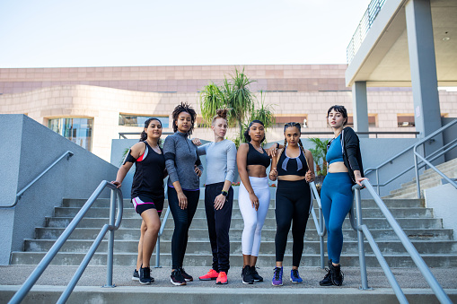 Full length shot of multi-ethnic women in sportswear standing together on stairs outdoors. Group of fit females standing in the city and posing.