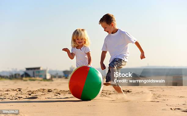 A Boy And A Girl Playing Ball At The Beach Stock Photo - Download Image Now - Beach, Beach Ball, Boys