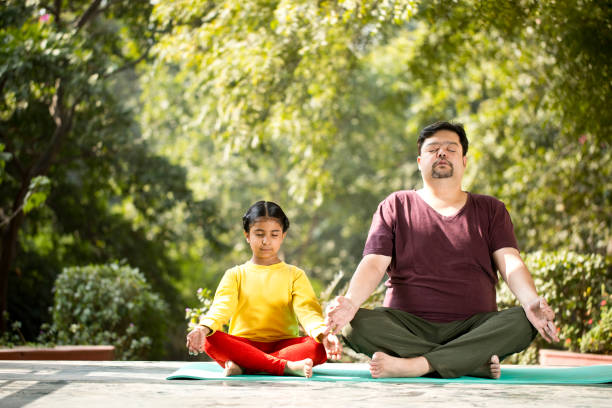 istock Father and daughter meditating at park 1194094519