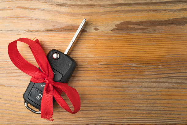 istock Car key with red bow on natural wooden table background. 1194096541