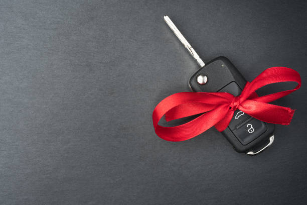 Car key with red bow on dark black slate plate.