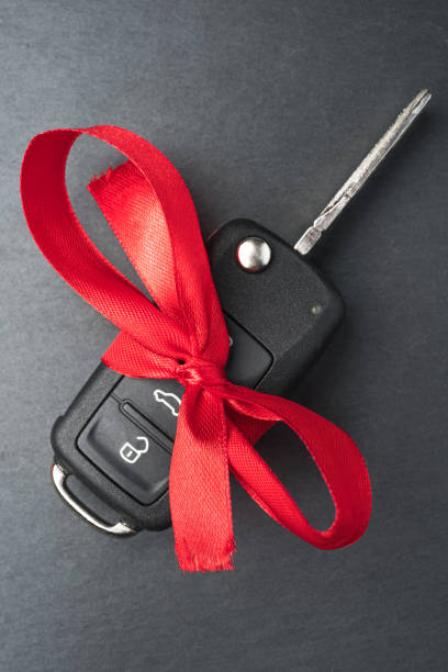 istock Car key with red bow on dark black slate plate. 1194096559