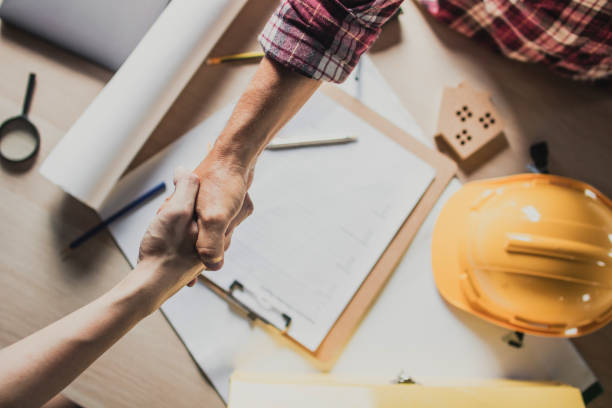 poignée de main de vue supérieure de l'ingénieur et de l'entrepreneur de bâtiment sur la table - entrepreneur en bâtiment photos et images de collection