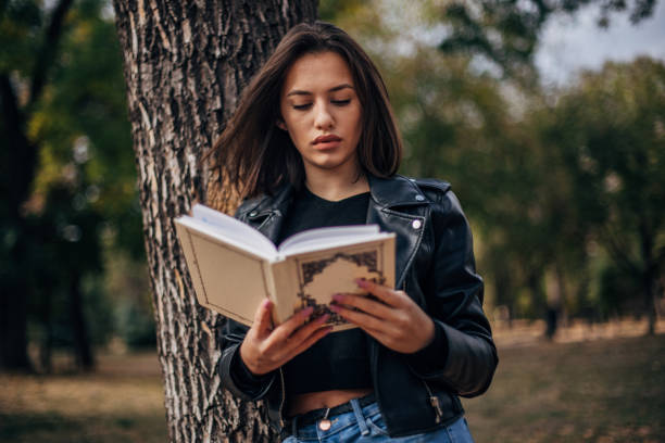 istock Beautiful young woman is reading a book 1194100615