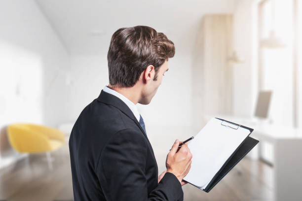 istock Young businessman with clipboard in blurry office 1194101143