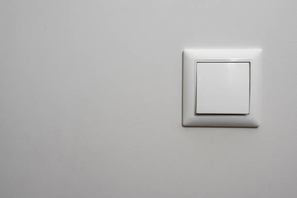 istock White light switch, a plastic mechanical switch of white color installed on a light gray wall. 1194103345
