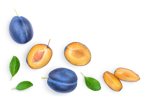 fresh blue plum and half with leaves isolated on white background with copy space for your text. Top view. Flat lay.