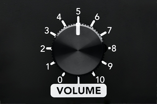 Volume control knob of a black amplifier with dial numbers. Close up view with copy space.