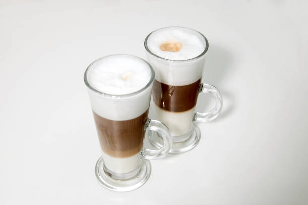 two clear glasses of latte macchiato coffee on white background