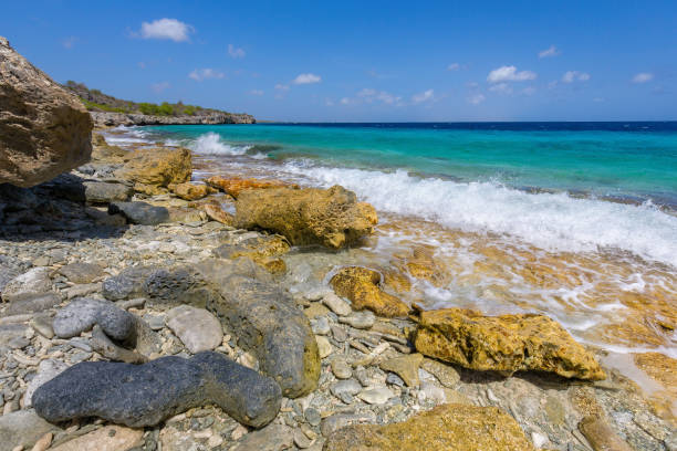 Landscape with rocks and stones at coast near sea of Bonaire. This photo was taken in the Washington Slagbaai National Park in the North of this beautiful island. I like the colorful yellow rocks lying at the beach with the blue color of the ocean and the sky.