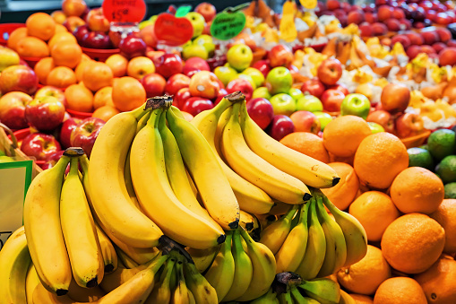 Heap of assorted organic fruits at display on the market stall. Banana, orange, apple.