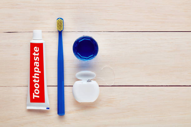 spazzolino da denti, dentifricio, filo interdentale e collutorio su tavolo di legno - bristle brush part foto e immagini stock
