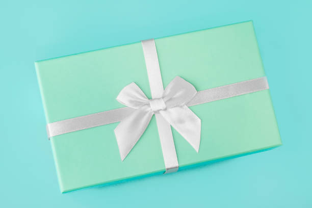 istock Gift box with a white silver bow, mint green on a mint turquoise background. Holiday gift minimal concept. Top view, flat lay, close-up. 1194112957