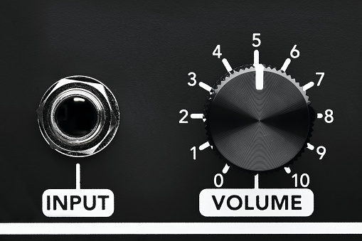 Close up detail of volume control knob and input jack of a black guitar amplifier. Close up view with copy space.