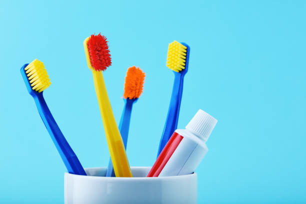 istock Multicolored toothbrushes and a toothpaste tube in a holder cup against blue background 1194114042