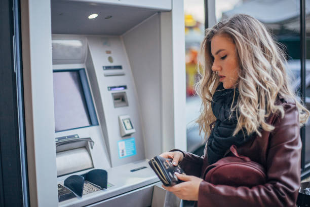 istock Pretty young woman is using ATM 1194115518