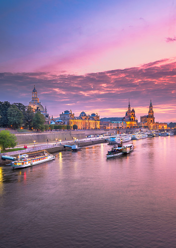 Dresden, Germany cityscape of cathedrals over the Elbe River at dusk.