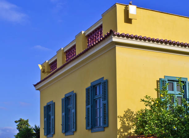 istock Neoclassical architecture yellow house with windows with blue shutters against clear sky. 1194120623