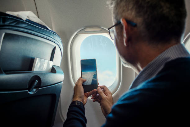 istock Male taking a photo with smartphone on plane 1194121907