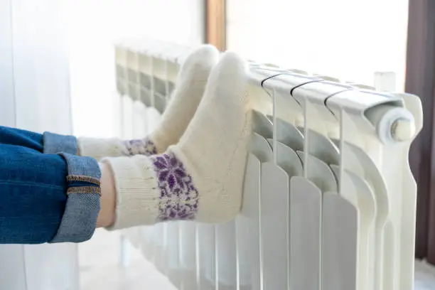Woman warming up with feet on heater