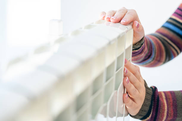 istock Woman touching warm radiator with both hands 1194123098