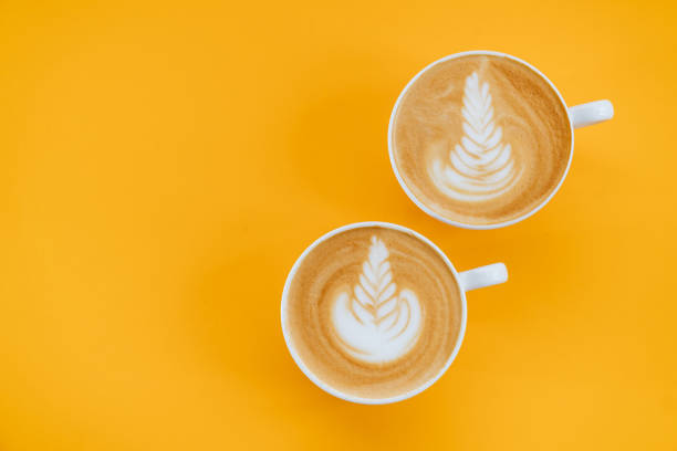 istock two cups of Latte coffee on yellow background. 1194123154