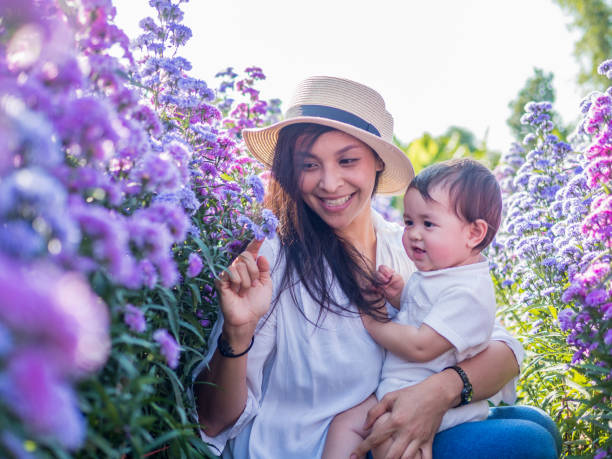 mutter und baby im blühenden garten. - baby toddler child flower stock-fotos und bilder