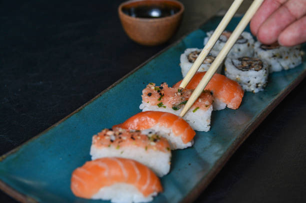 primer plano de un niguiri sushi con palillos. comida japonesa, roll con salmón, niguiri. restaurante - niguiri sushi fotografías e imágenes de stock