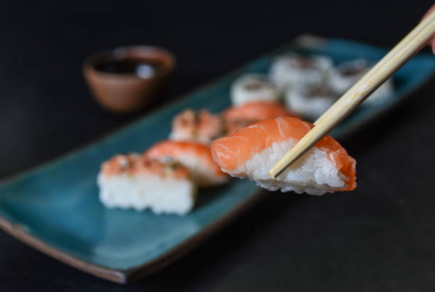 primer plano de un niguiri sushi con palillos. comida japonesa, roll con salmón, niguiri. restaurante - niguiri sushi fotografías e imágenes de stock