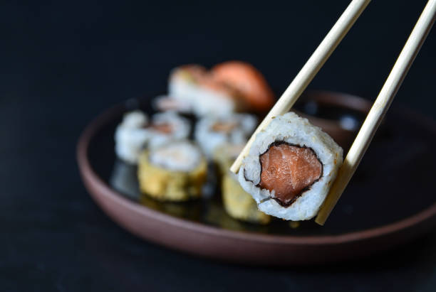 z bliska rolki sushi z pałeczkami. japońskie jedzenie, roll z łososiem, niguiri, gorące bułki. - niguiri sushi zdjęcia i obrazy z banku zdjęć