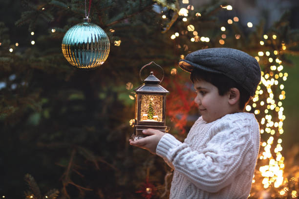 istock Christmas vintage background with boy, Christmas tree, and light bulbs. 1194132478