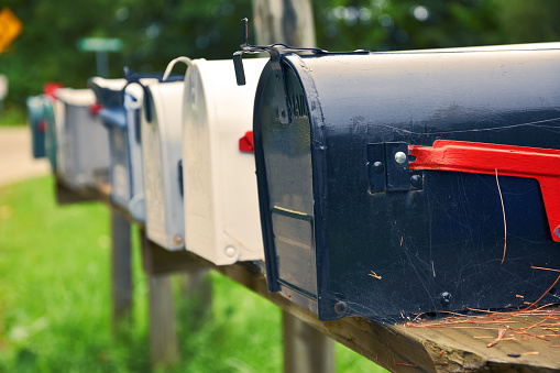 An isolated row of metal US mail boxes on wooden post in the countryside. Spider webs in one of them. Mail concept. New York City. United States.