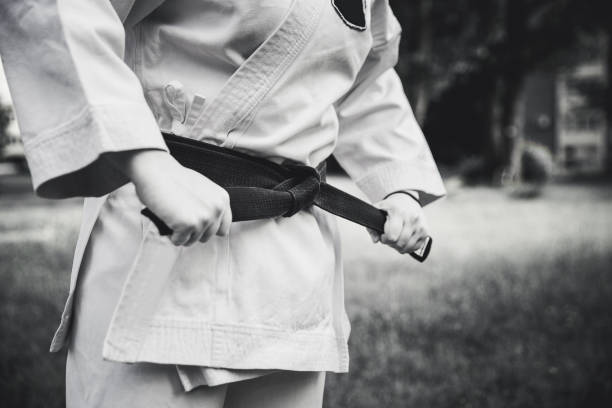 mujer luchadora apretando el cinturón de karate - martial arts women tae kwon do black belt fotografías e imágenes de stock