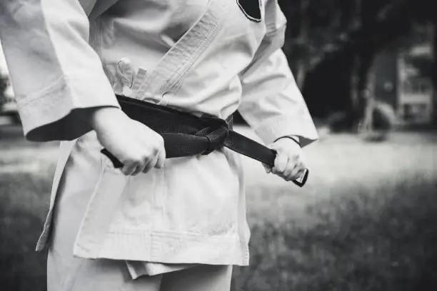 Young female fighter tightening karate belt outdoors
