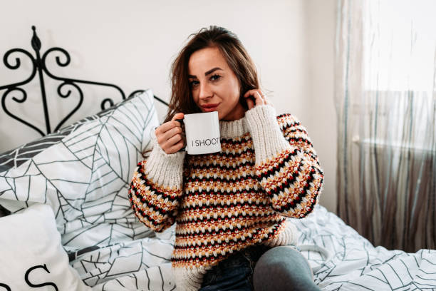 istock Young woman sitting in bed and drinking coffee 1194153738