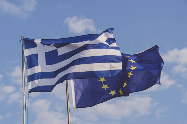 欧州連合(eu)の旗の横を飛ぶギリシャの国旗 - eurozone debt crisis ストックフォトと画像