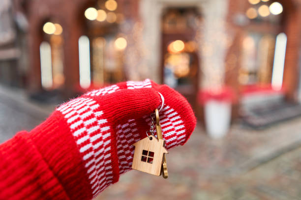 mortgage or rent concept. hand in red mitten holding key with house shaped keychain. real estate, hypothec, moving home or renting property. christmas mood in blurred background. - key real estate key ring house key imagens e fotografias de stock