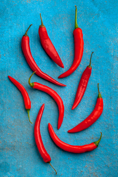 istock Red chili peppers fresh overhead arrangement on rustic blue background 1194156833