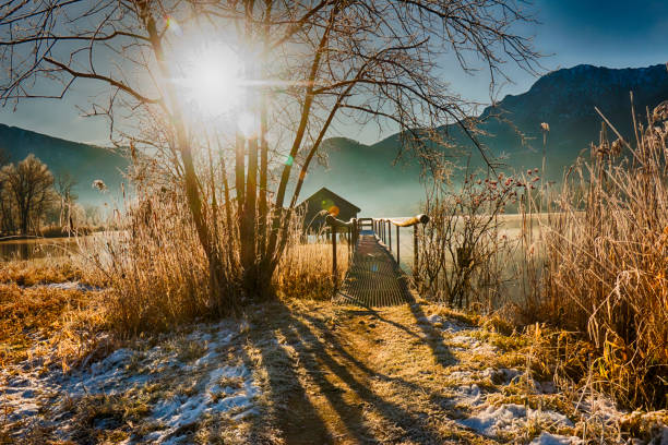 bateau sur un lac de montagne sur un matin givré avec le brouillard et le soleil levant - frozen cold lake reed photos et images de collection