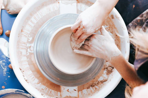 istock Process of creating and formation a white clay ceramic plate. Professional potter is engaged in modeling clay plates. Potter works in a workshop 1194160659