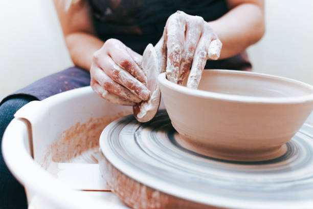 Process of creating and formation a white clay ceramic plate. Professional potter is engaged in modeling clay plates. Potter works in a workshop