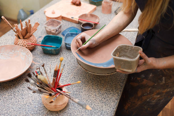 istock Potter woman paints a ceramic plate. Girl draws with a brush on earthenware. Process of creating clay products 1194160712