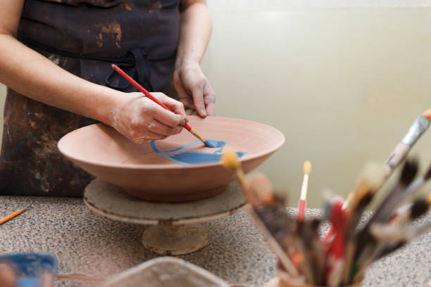 istock Potter woman paints a ceramic plate. Girl draws with a brush on earthenware. Process of creating clay products 1194160725
