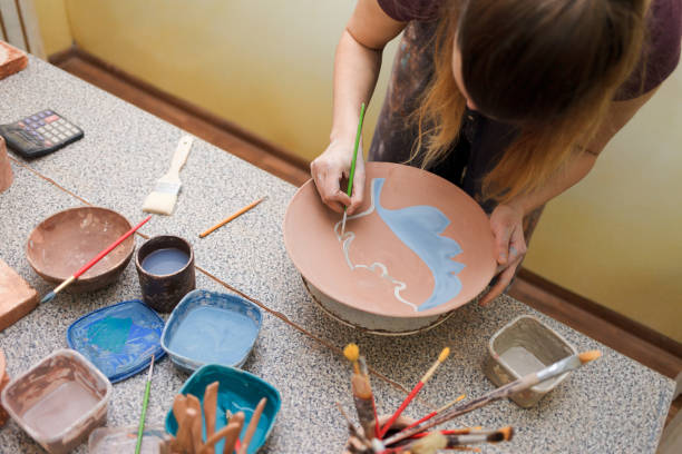 istock Potter woman paints a ceramic plate. Girl draws with a brush on earthenware. Process of creating clay products 1194160735