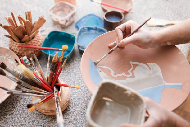 istock Potter woman paints a ceramic plate. Girl draws with a brush on earthenware. Process of creating clay products 1194160744