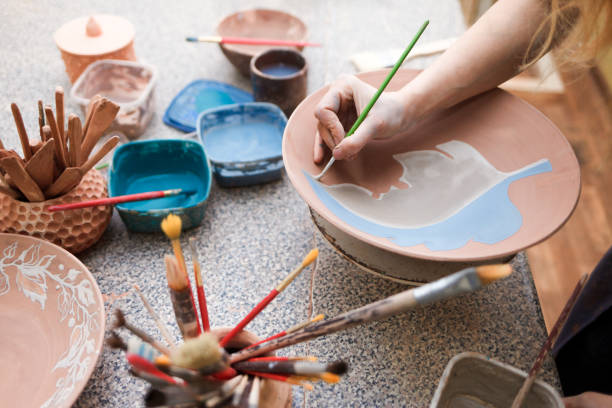 istock Potter woman paints a ceramic plate. Girl draws with a brush on earthenware. Process of creating clay products 1194161264