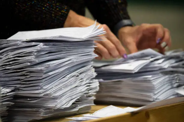 a pair of hands counting piles of ballot papers during an election
