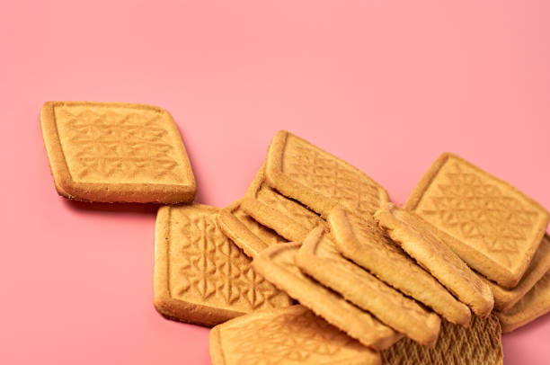 istock Scattered whole square cookies on pink desk on kitchen. Space for text 1194163931